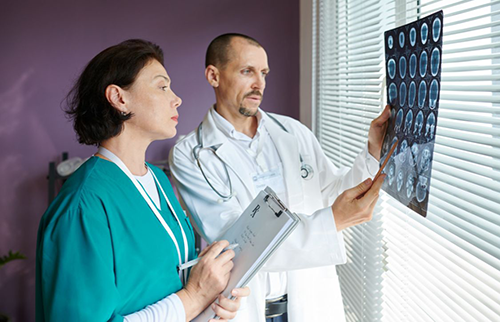 Nurse along with doctor reviewing hydrocephalus patient brain scans